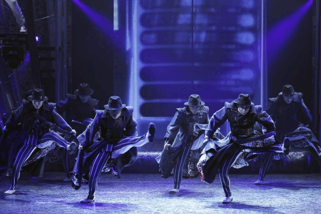 シルク・ドゥ・ソレイユのステージで「Smooth Criminal」を披露するパフォーマーたち。黒い帽子とコート姿で力強くダンスをする様子。